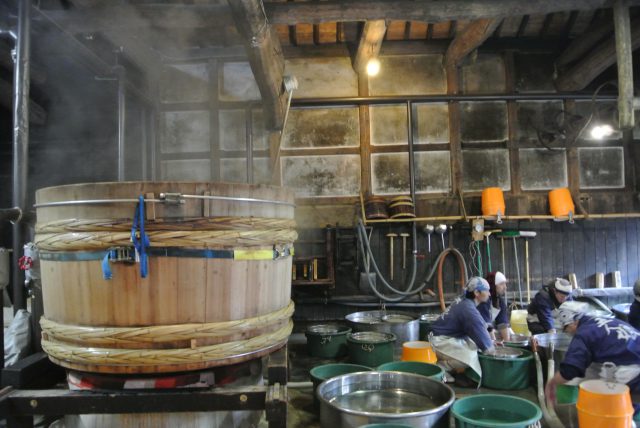 rewers deftly rinsing the raw rice. For this process, they use the underground water drawn from the well in Kōzaki Shrine located behind the brewery, a tradition they have been keeping since inception. And as a matter of course, they rinse the rice with bare hands no matter how cold the winter water may be. 
After the thorough rinsing process, they transfer the cleaned rice to a huge cauldron to move on to the next process – rice steaming.
